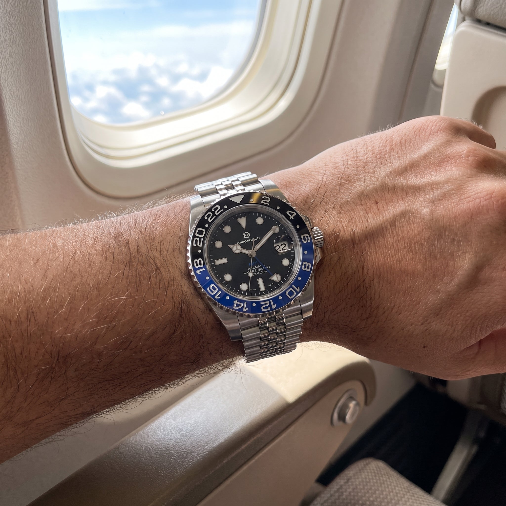 Chrono Mod GMT worn on the wrist by an airplane window, natural light