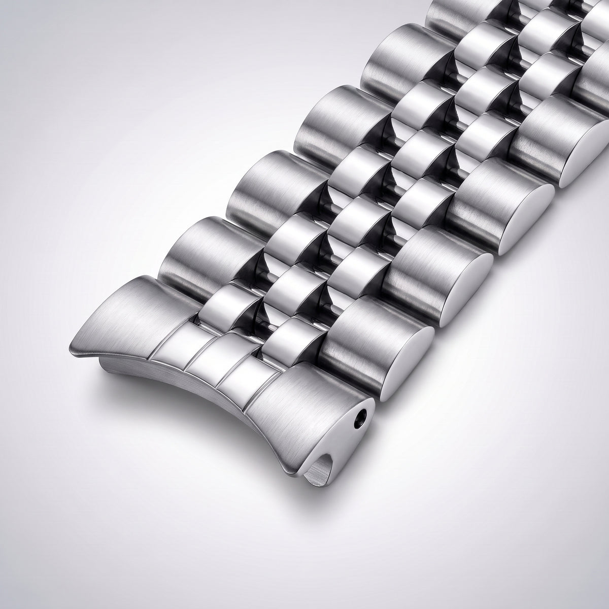 Close-up of the curved end link, hollowed into a concave crescent so it sits flush against a round 20 mm lug watch case